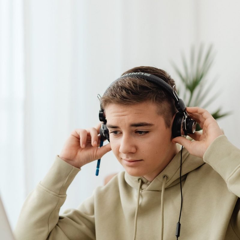 Teenager wearing headphones studying at a laptop at home